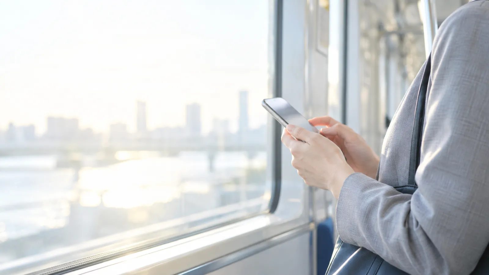 電車内でスマホを見ている通勤中の人